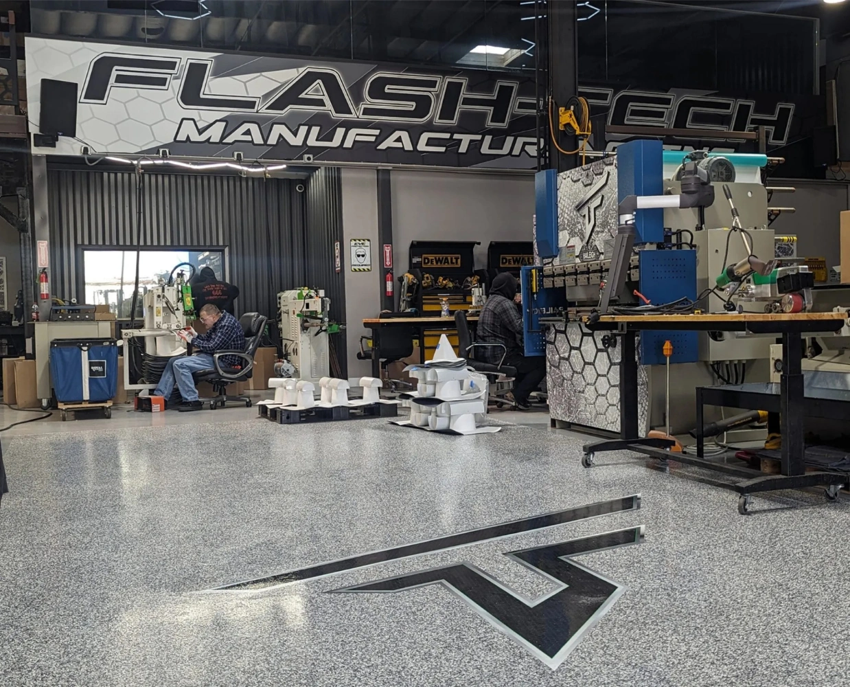 Flash-Tech Manufacturing production floor with technicians operating fabrication equipment for single-ply roofing accessories.